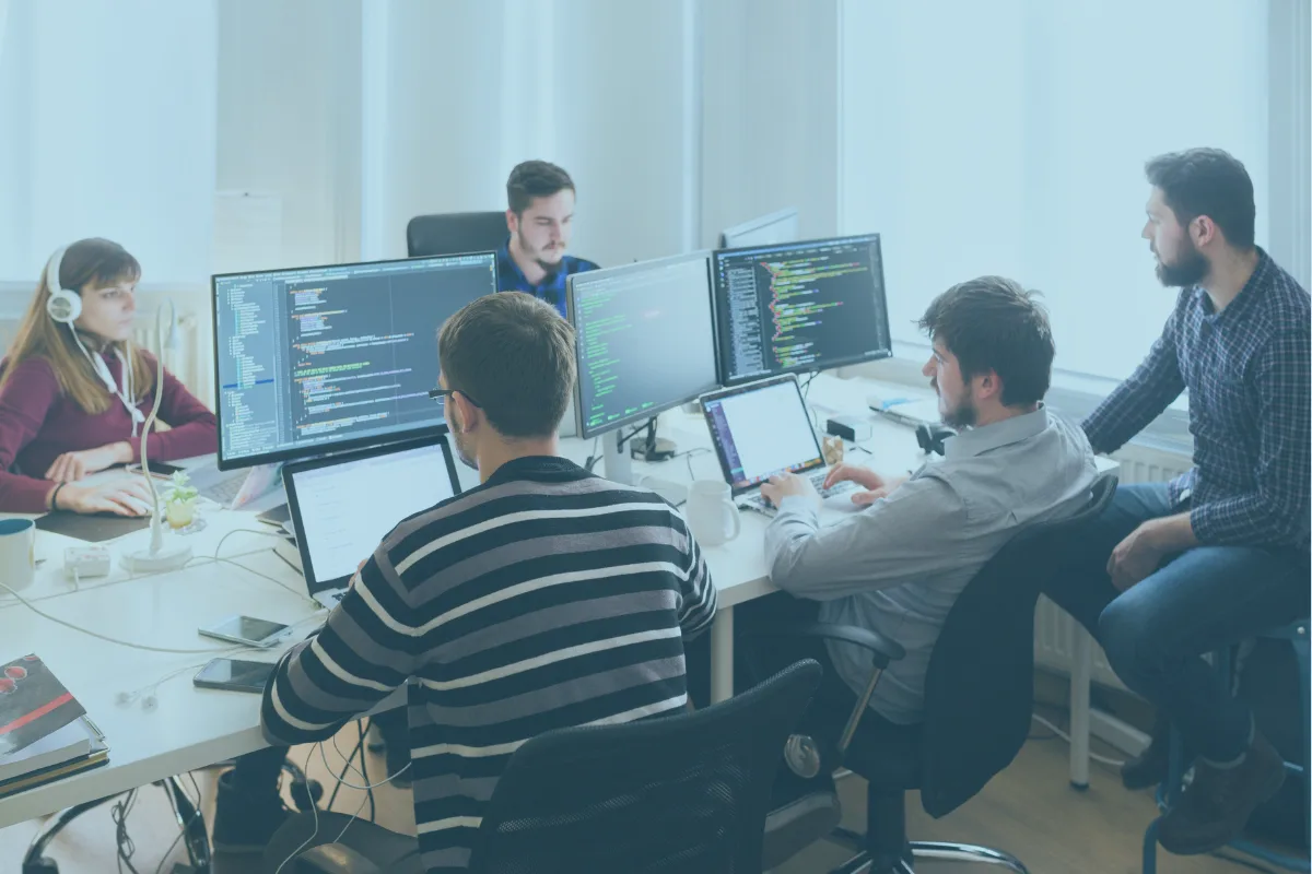 Entwicklerteam an Arbeitsplätzen mit mehreren Monitoren und Code auf den Bildschirmen